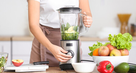 Young woman making healthy smoothie in kitchen