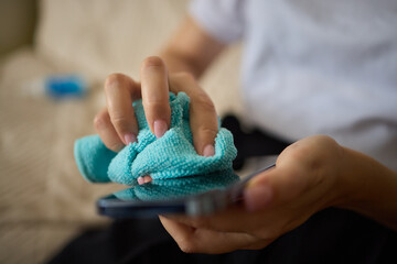 A person is using a microfiber cloth to clean their smartphone for hygiene purposes