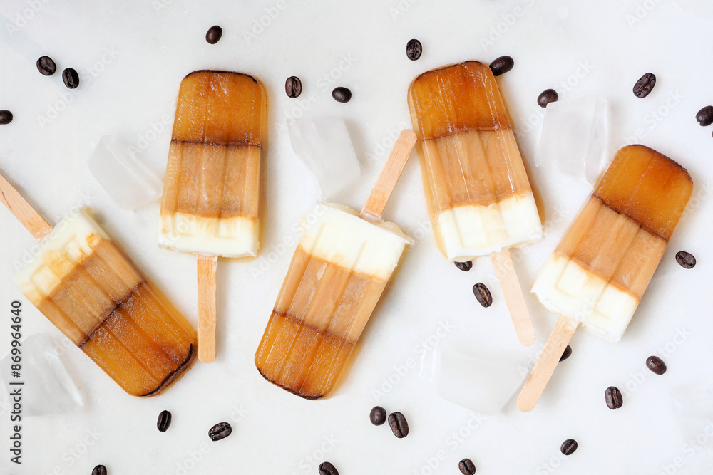 Poster refreshing coffee and cream ice pops. overhead view scattered on a white marble background.