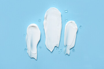 Samples of cosmetic cream on blue background