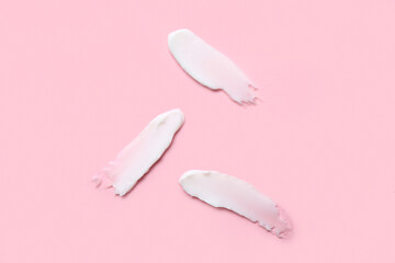 Samples of cosmetic cream on pink background