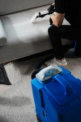 Extracting dust and dirt, removing spots from sofa using extractor to clean upholstered furniture....