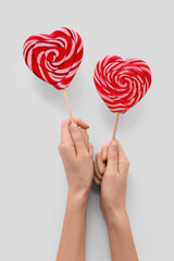 Female hands with sweet heart-shaped lollipops on white background, closeup. Valentine's Day celebration