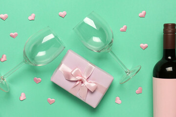 Composition with bottle of wine, gift box and glasses for Valentine's day on turquoise background