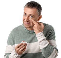 Mature man putting in contact lenses on white background