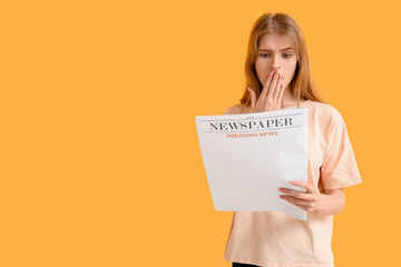 Naklejka premium Emotional young woman reading newspaper against color background