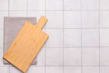 Cutting board and napkin on white tile background. Top view