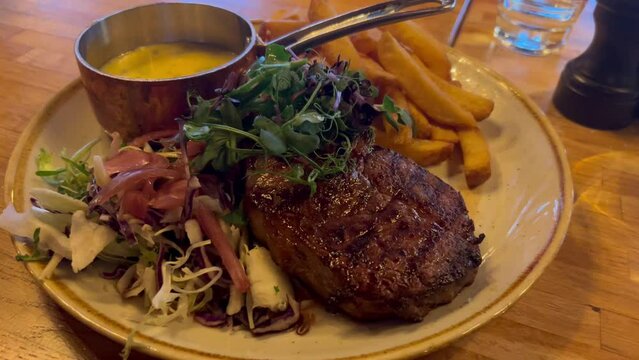 Juicy steak medium rare beef with baked potatoes on white plate served in restaurant. Top view, flat lay. Close up medium rare steak being cut on a plate with roast potatoes and creamy sauce. Served