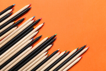 Heap of color pencils on orange background