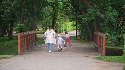 Caucasian Female Mother Spending Time with Kids on a Walk in City Park