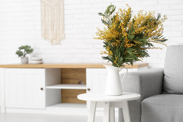 Vase with beautiful mimosa flowers on table in light living room