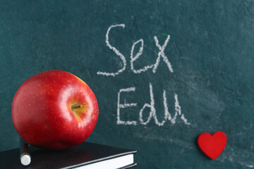 Apple, book and written text SEX EDU on dark background. Sex education