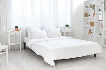 Interior of light bedroom with tables and shelf unit