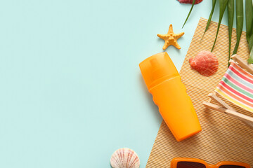 Bottle of sunscreen cream, deckchair and palm leaves on cyan background