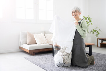 Senior (elderly) woman's whole body with dirt and clean laundry and towels that feel great.