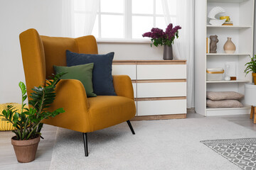 Cozy armchair with cushions near houseplant in living room