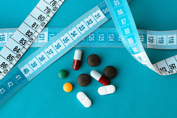 Antibiotic tablets (amoxicillin and norfloxacin), activated charcoal and flu medicine are seen next to a measuring tape. Some medications can cause side effects that, over time, can cause weight gain.