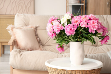 Cozy sofa and coffee table with peonies in interior of living room