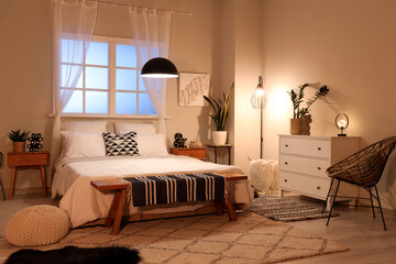 Comfortable bed with glowing lamps in interior of modern bedroom