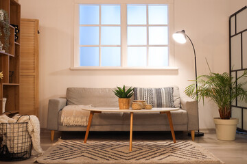 Interior of stylish living room with comfortable sofa, coffee table and glowing lamps