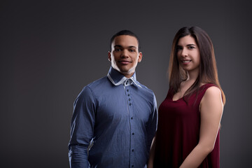 Young multiethnic couple smiling on grey background