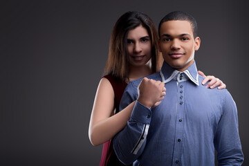 Woman holding man's arm smiling on grey background