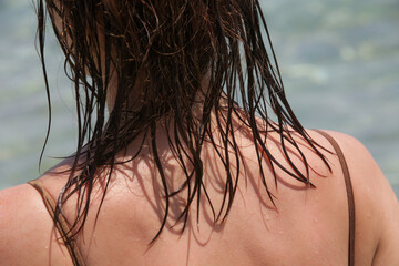 Woman's hair on the beach. Wet hair close up image. Hair damage due to salty ocean water and sun, summertime hair care concept.