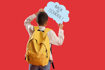 Little boy holding speech bubble with text BACK TO SCHOOL on red background