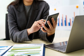 A businesswoman in a grey suit works from home, specializing in policy and planning analysis, managing financial tasks at desk with a whiteboard and expertise in accounting and financial services.