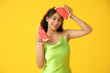 Happy young African-American woman with fresh watermelon on yellow background