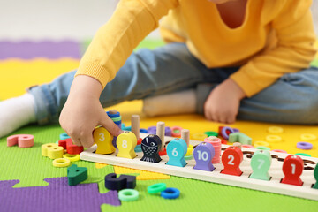 Fototapeta premium Little boy playing with game Fishing for Numbers on puzzle mat, closeup. Kindergarten activities for learning mathematics