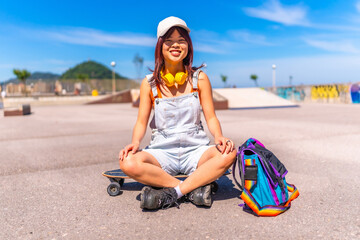 Asian woman sitting on skateboard in a park