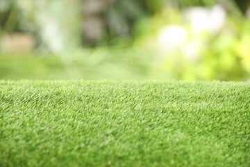 Naklejka premium Green artificial grass against blurred background, closeup