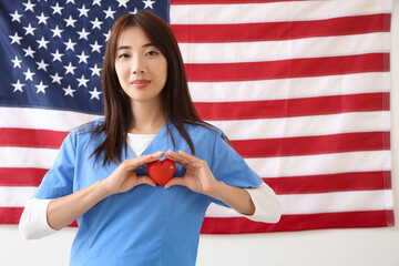 Female Asian doctor with heart against USA flag. Labour Day celebration