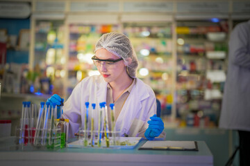 Top view of female scientist Experimenting through tubes of chemical liquids and plant samples. In the laboratory with tabletop test samples and modern data sheets By testing safely and cleanly.