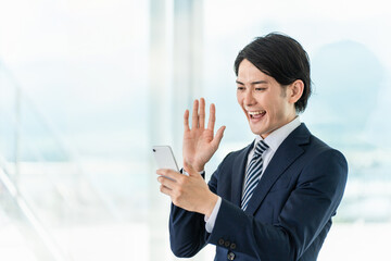 スマホアプリを使うビジネスマン・WEB会議・オンライン会議・テレビ電話
