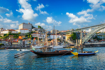 Obraz premium View of Porto city and Douro river with traditional boats with port wine barrels and sailing ship from famous tourist viewpoint Marginal de Gaia riverfront. Porto, Vila Nova de Gaia, Portugal