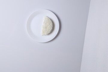 white plate with a piece of rice on it. The rice is cut in half and is sitting on the plate