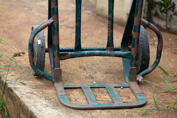 Old rusty wheelbarrow on cement floor in garden, stock photo