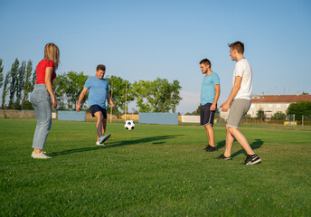 Mixed Group of four people male and female playing soccer on the pitch, team building concept