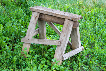 Old wooden construction stand on the grass. Construction goat.