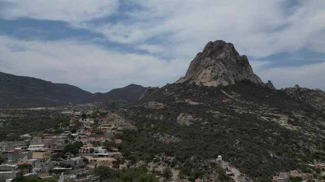 Pena De Bernal mountain is nestled in a valley, accompanied by a quaint town in Queretaro, Mexico.