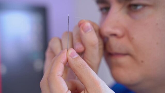 The concentrated face of man tries to get thread into hole of needle, misses, freaks out, takes out his anger on his family Age-related changes, blurred vision, nervous tailor at work Missed target