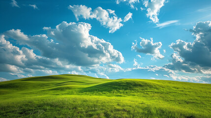 Landscape view of green grass on slope with blue sky and clouds background.