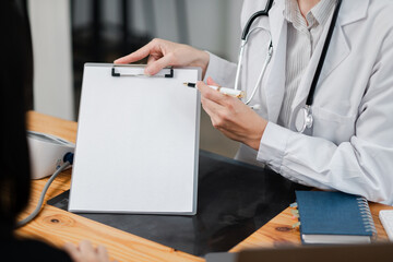 Healthcare professional explaining medical results to a patient using a clipboard in a modern clinic setting.