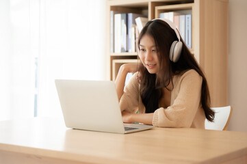 Young asian woman wearing headset while working on computer laptop at house. Work at home, Video conference, Video call, Student learning online class