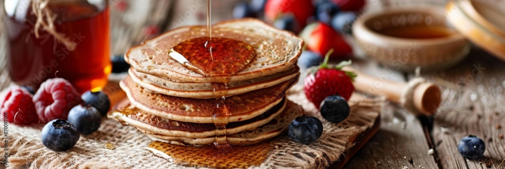 Poster a rustic table setting with a stack of buckwheat flour pancakes fresh fruit and a jar of homemade ma