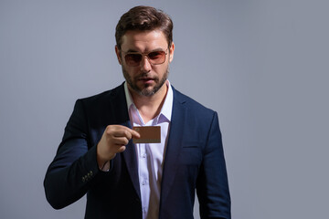 Credit card concept. Caucasian millennial successful 40s business man holding banking card isolated on gray background, studio portrait. People lifestyle concept. Purchasing and cashback rewards.