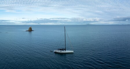 Fototapeta premium Sailboat docked in the Hauraki Gulf. Matakatia with an island in the background, Whangaparoa, Auckland, New Zealand.
