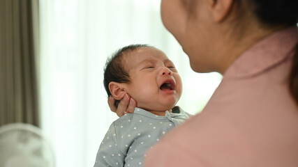 Loving asian mother comforting baby son in her arms. Childcare and motherhood concept